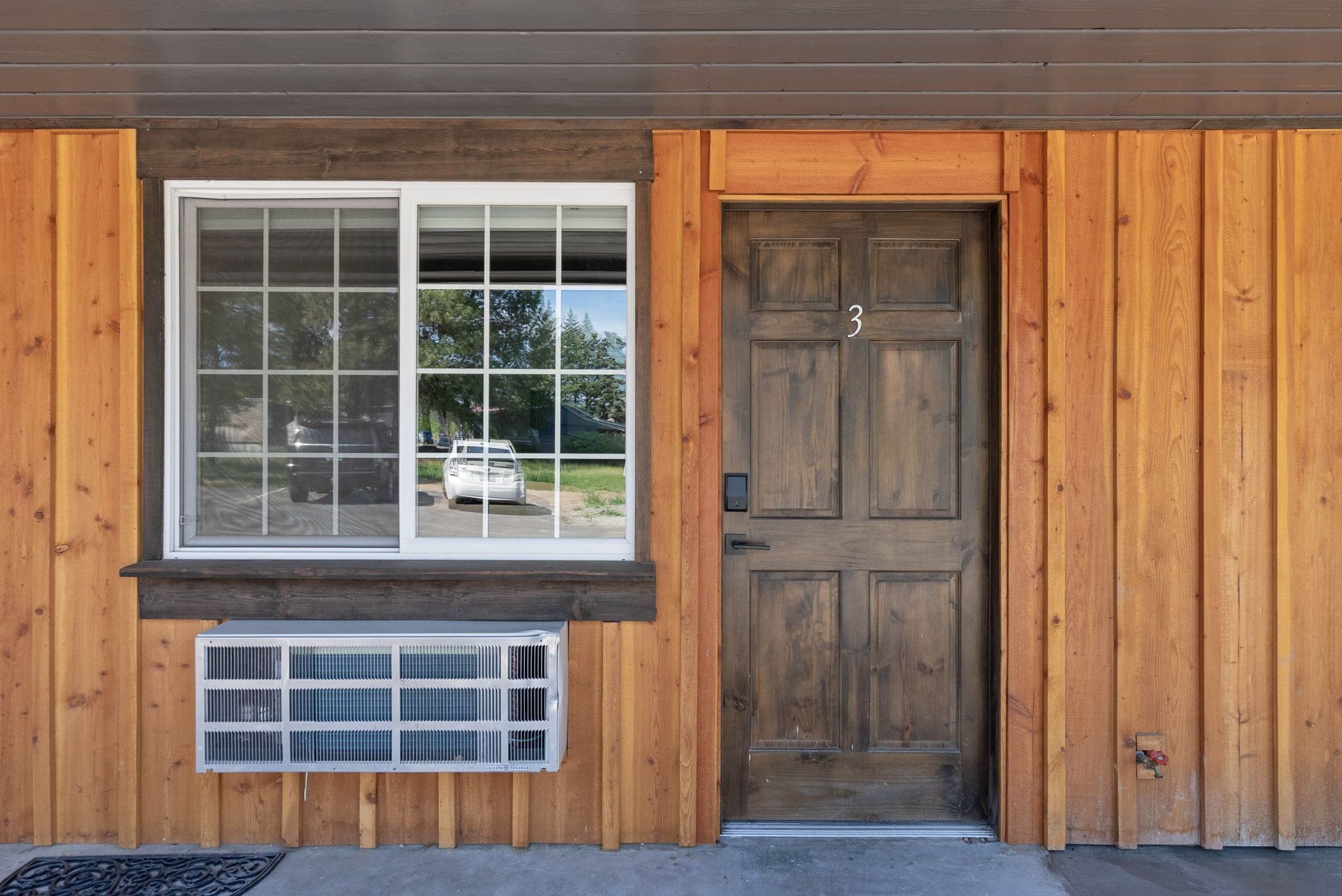 A wooden house with a large window and a door.