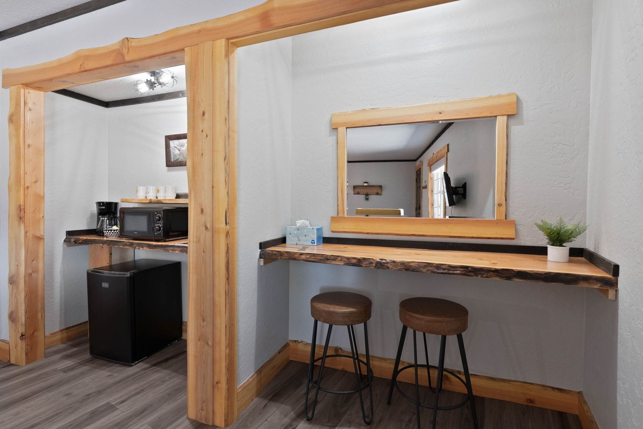 A compact kitchen with a microwave, refrigerator, and bar stools.