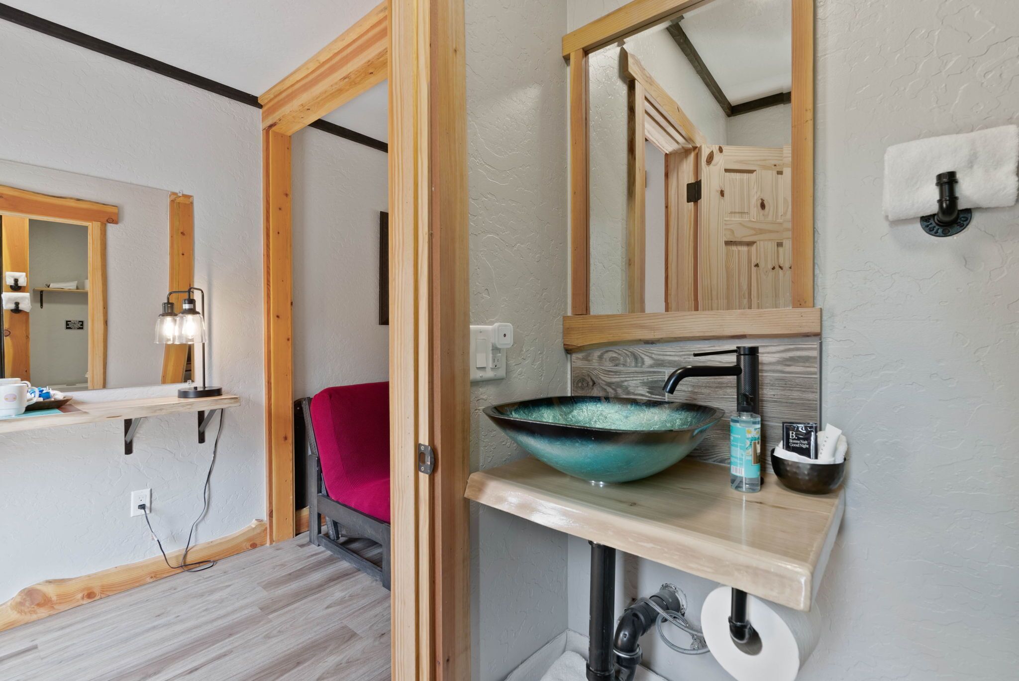 A bathroom with a wooden vanity, a large mirror, a bowl sink, and a towel rack.