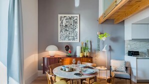 Zona pranzo con tavolo rotondo apparecchiato per quattro persone, circondato da sedie. Sopra il tavolo, un'ampia opera d'arte astratta.