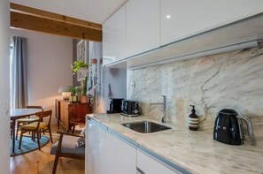 A modern kitchen with a marble countertop, a sink, a coffee maker, and a toaster.