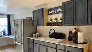 A kitchen with dark cabinets, a stainless steel refrigerator, a sink, and holiday decorations. - Country Escape Next DOOR Rental - Sleeps 6 - Stay upstairs in the trees  (Chesapeake)