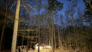 A cabin with a porch and picnic tables, surrounded by tall trees and a clear night sky. - Country Escape Next DOOR Rental - Sleeps 6 - Stay upstairs in the trees  (Chesapeake)