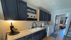 A modern kitchen with dark cabinets, a granite countertop, a sink, and a built-in stove. - Country Escape Next DOOR Rental - Sleeps 6 - Stay upstairs in the trees  (Chesapeake)