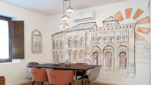 A dining area with a table, chairs, and a mural of a building. - ALFICEN CERVANTES 5 COLLECTION (Toledo)