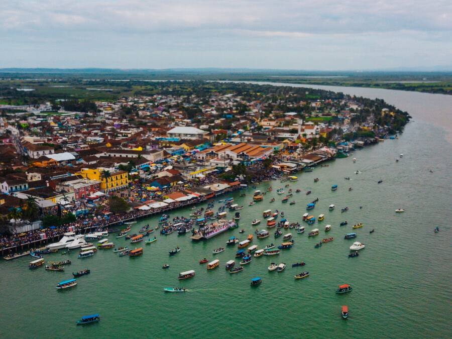 Vista aérea de uma cidade costeira com edifícios densos ao longo da orla marítima e vários barcos na água.