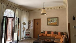 A living room with a sofa, a baby stroller, a door with a floral design, and a painting on the wall. - Rita House le Petit Paradis sur Terre (Marrakech)