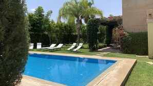 A swimming pool with lounge chairs, surrounded by greenery and a pergola. - Rita House le Petit Paradis sur Terre (Marrakech)