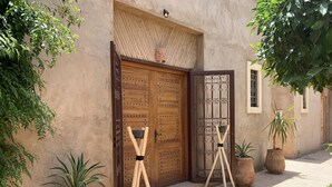 A courtyard with a wooden door, potted plants, and a tiled floor. - Rita House le Petit Paradis sur Terre (Marrakech)