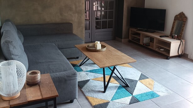 A modern living room with a grey sectional sofa, a wooden coffee table, a TV on a wooden stand, and a patterned rug. - Maison de Vacances, Proche de la Plage! (Fréjus)