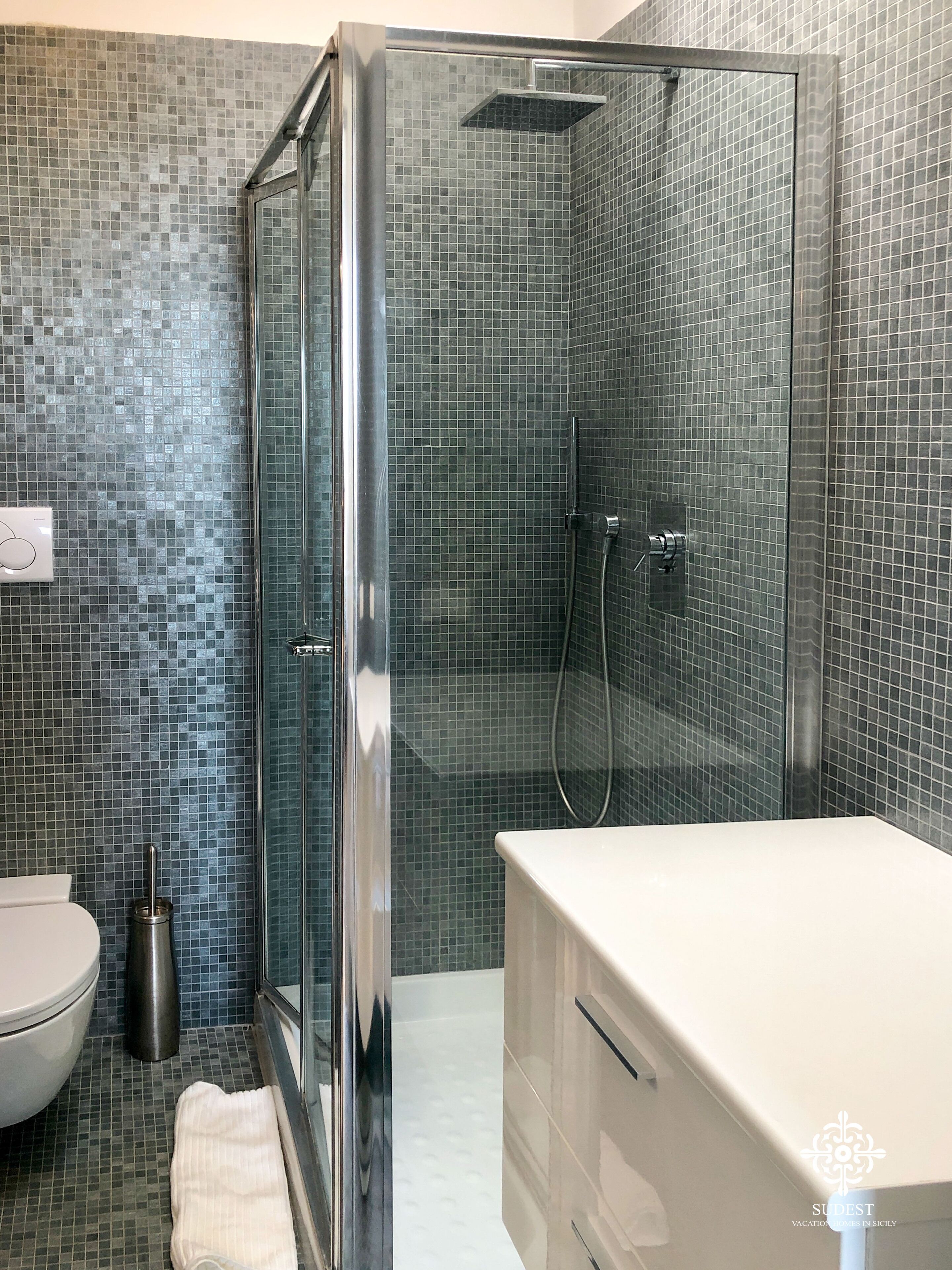 A modern bathroom with a glass-enclosed shower, a white toilet, and a white sink.