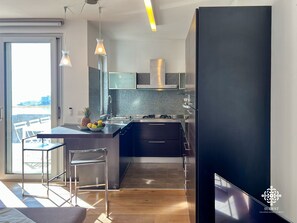 Una cocina moderna con una isla grande, electrodomésticos de acero inoxidable y vistas al mar.