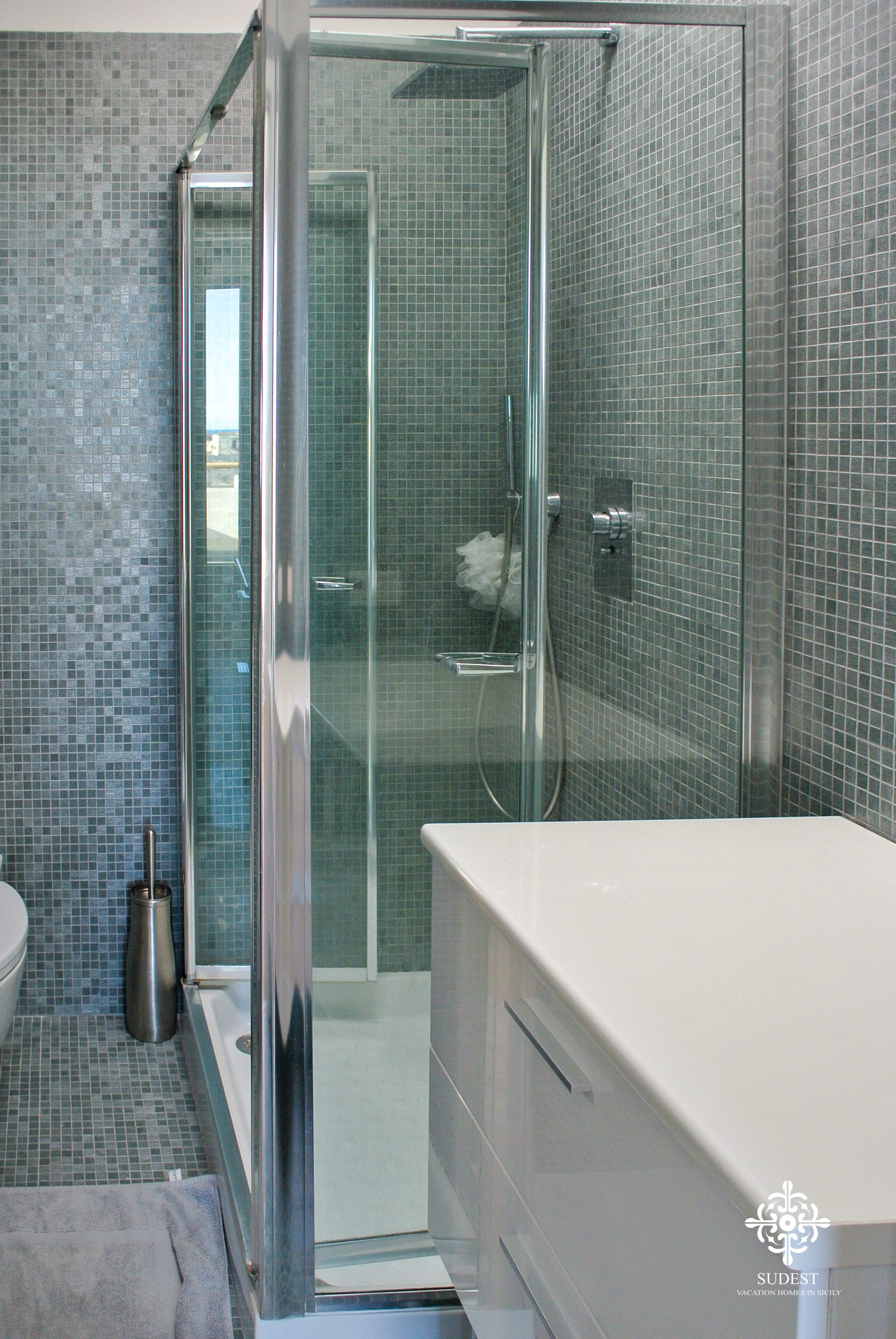 Un baño moderno con ducha envuelta en vidrio, bañera blanca y piso de baldosas.