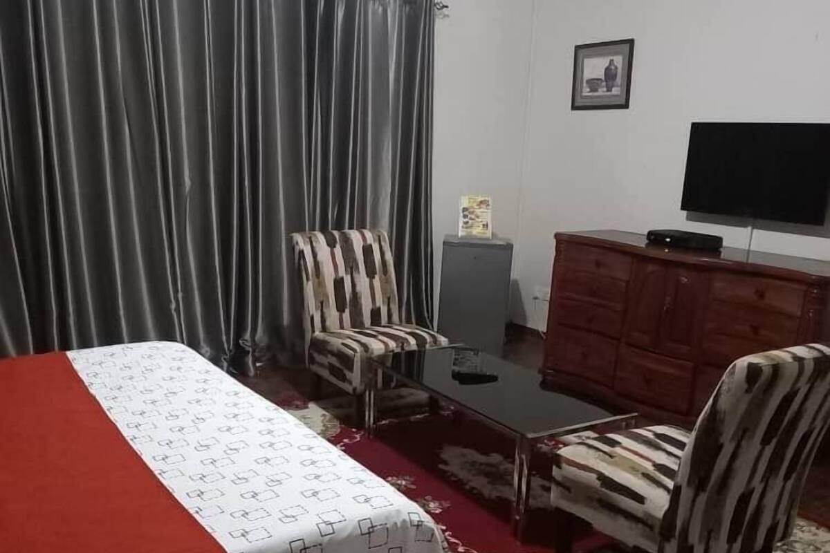 Una habitación de hotel con cama, escritorio, televisión y armario.