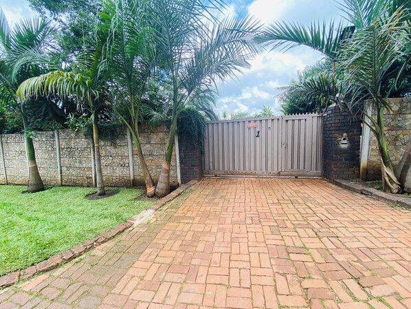 A gated entrance with a brick pathway leading to a stone wall.