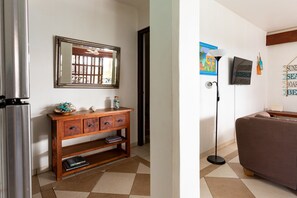 A room with a wooden cabinet, a mirror, a floor lamp, and a sofa.