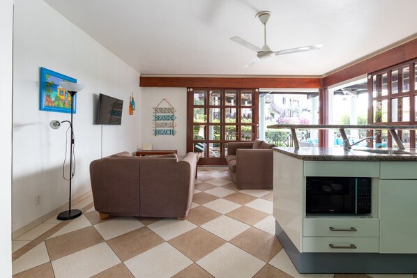 A spacious living area with a sofa, a dining table, and a kitchen with a built-in microwave.