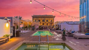 A rooftop pool area with a pool, lounge chairs, and a building in the background.