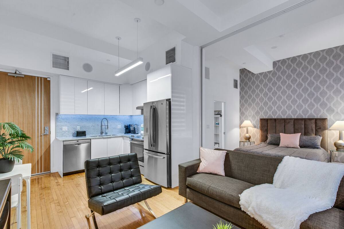 Un appartement moderne comprenant un coin cuisine, un espace repas, un salon avec un canapé et un lit.