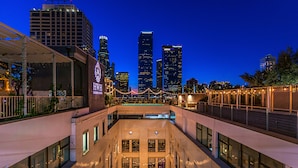 A modern building with a courtyard, large windows, and a view of the city skyline at dusk.