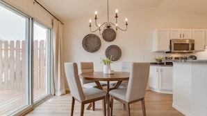 Une cuisine moderne avec des meubles blancs, un four à micro-ondes encastré et un coin repas comprenant une table ronde et quatre chaises.