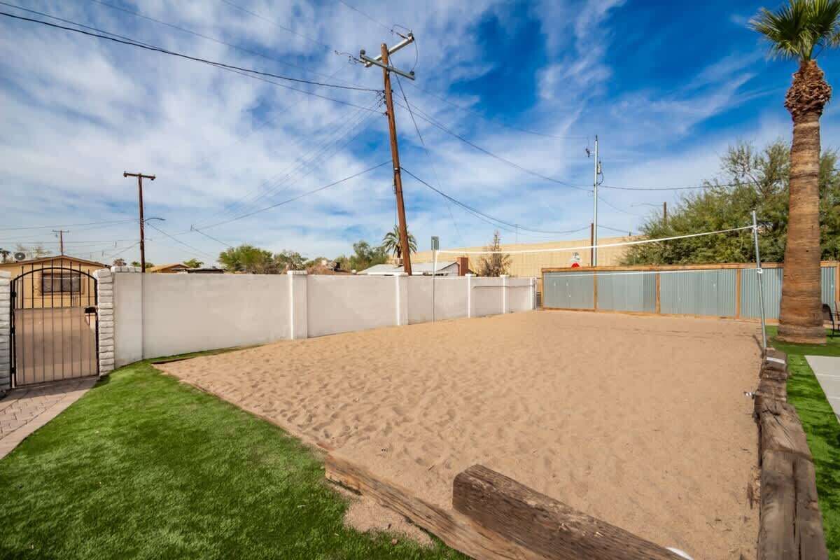 A fenced backyard with a sandy area, a wooden fence, and a palm tree.