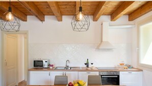 A modern kitchen with wooden beams, a wooden dining table, white cabinets, and pendant lights.