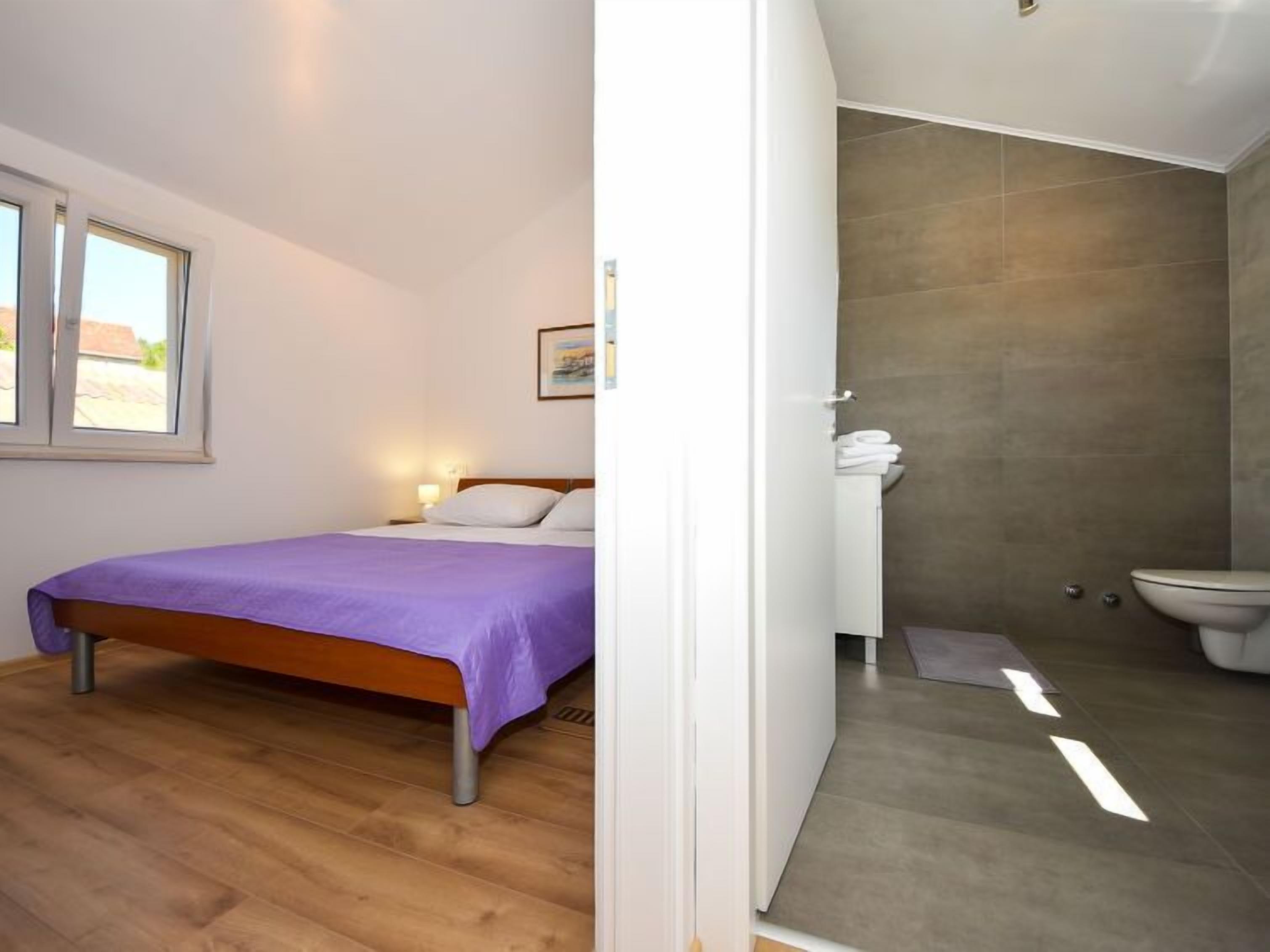 Un dormitorio con cama, ventana y baño con inodoro y ducha.