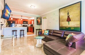 Relax in this stylish living space with a comfortable sofa, flat-screen TV, and modern kitchen amenities.
