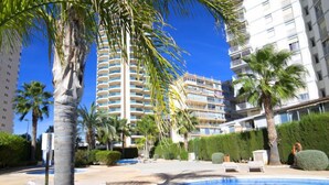 Un resort con piscina, palme e grattacieli sullo sfondo.