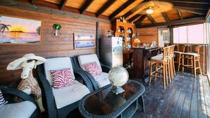 A cozy cabin interior with a wooden ceiling, a dining area with wooden chairs, a bar area with a refrigerator, and two sofas with patterned cushions. - Vacation home Noosa by Interhome (Calpe/Calp)