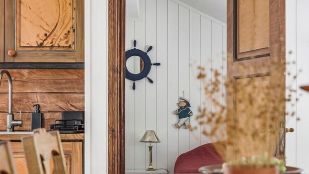 Et træbord med stole, et skibsråd, en lille figur og en lampe.