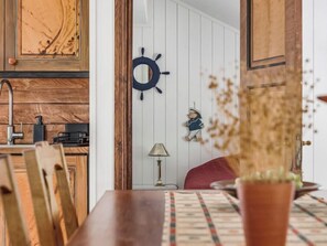 A wooden dining table with chairs, a ship's wheel, a small figurine, and a lamp. - Vacation home Jennys by Interhome (Jämjö)