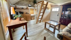 Ein kompakter Wohnraum mit einer Küche, Essbereich und einem Schlafzimmer auf dem erhöhten Zwischenstock.