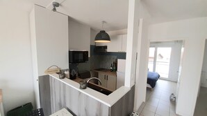 A compact kitchen with a microwave, sink, and a hanging light fixture.