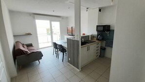 A compact kitchen with a dining area, a sofa, and a TV.