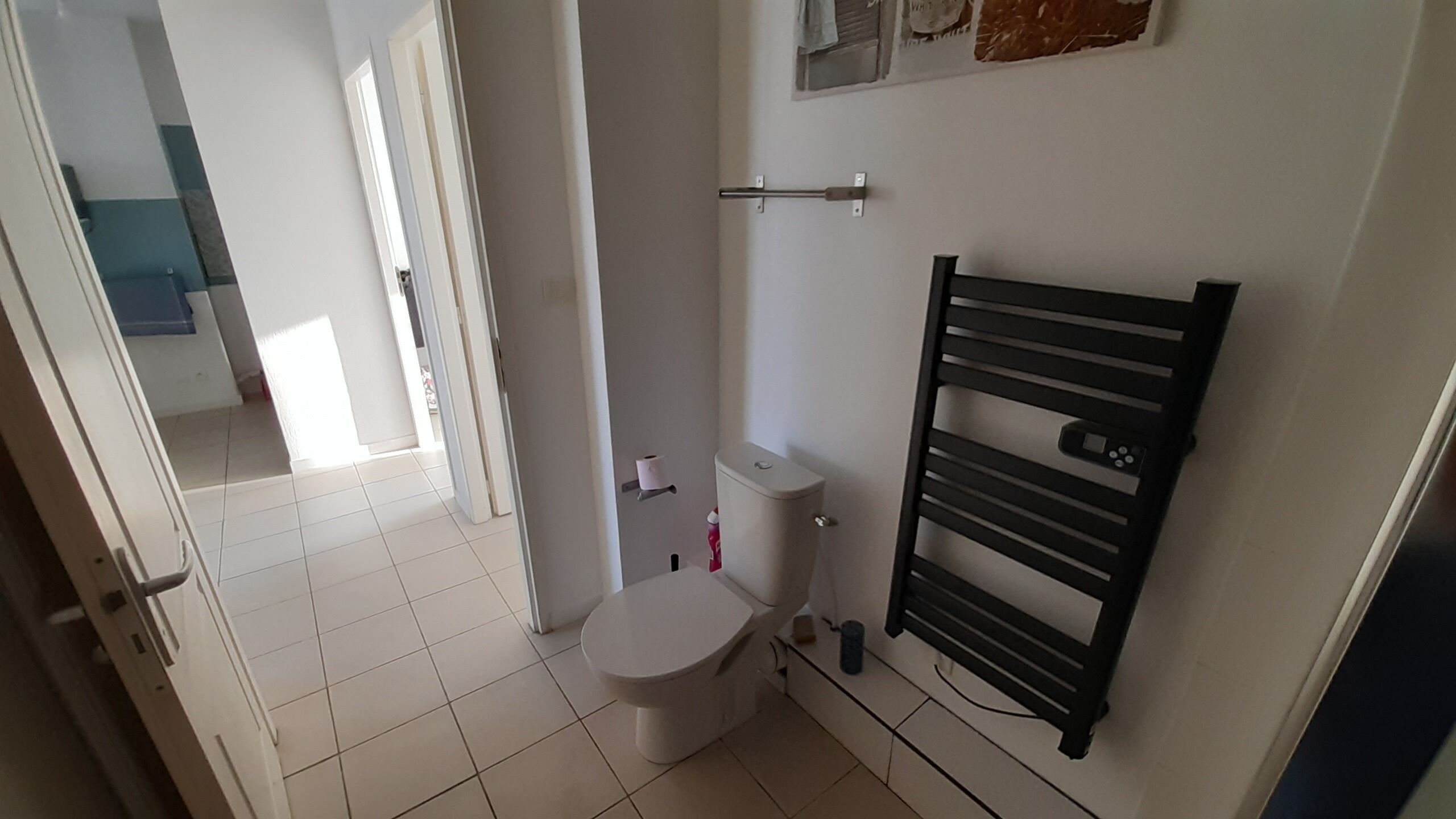 Ein kleines Badezimmer mit Toilette, Handtuchhalter und Duschbereich.
