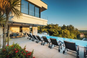 A modern outdoor pool area with lounge chairs and a dining setup. - 4BD villa for up to 8 with large swimming pool, jacuzzi, sauna, gym, bocci (Brnobići)