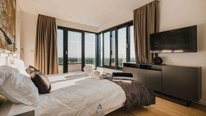 A modern hotel room with a large bed, a flat-screen TV, and a view of the cityscape through floor-to-ceiling windows. - 4BD villa for up to 8 with large swimming pool, jacuzzi, sauna, gym, bocci (Brnobići)
