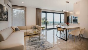 A modern living room with a sofa, a coffee table, and a dining area with chairs. - 4BD villa for up to 8 with large swimming pool, jacuzzi, sauna, gym, bocci (Brnobići)