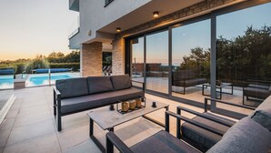 A modern outdoor patio with a pool, a sofa, and a dining area. - 4BD villa for up to 8 with large swimming pool, jacuzzi, sauna, gym, bocci (Brnobići)