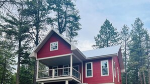 Una casa roja con balcón, rodeada de árboles.