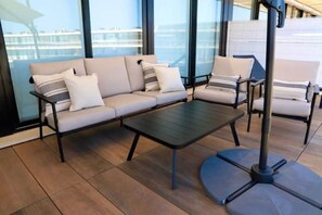Uma área de estar moderna ao ar livre, com um sofá, poltronas e uma mesa de centro.