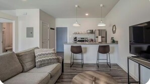 A modern kitchen with a dining area, a sofa, and a TV.