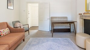Ein Wohnzimmer mit einer Couch, einem Sessel, einem Teppich mit Muster, einem Tisch und einem Kamin.