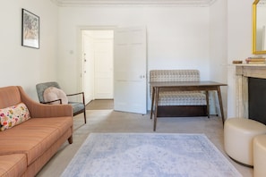 A living room with a sofa, a chair, a patterned rug, a table, and a fireplace.