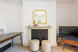 A room with a fireplace, a mirror, a bench, and two stools.
