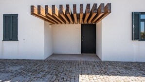 A building with a white exterior, a black door, and a cobblestone ground. - Casa São João a 400 Metros da Praia com Jardim (Arcozelo)