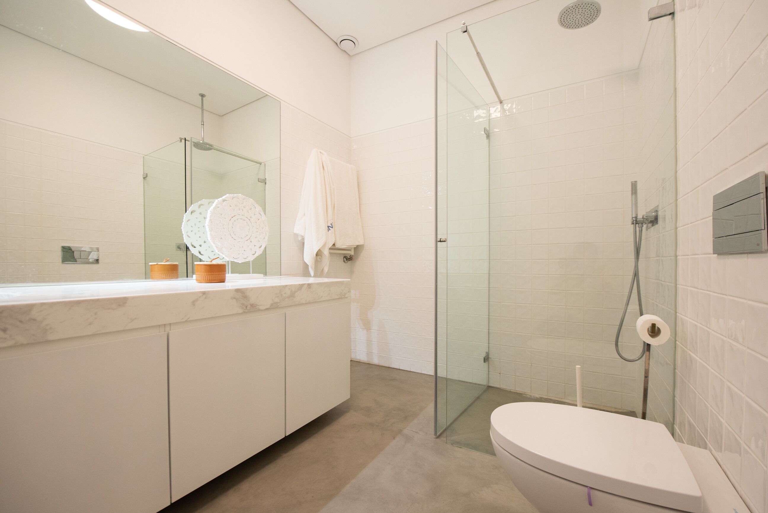 A modern bathroom with a glass shower enclosure, a marble countertop, and a large mirror.