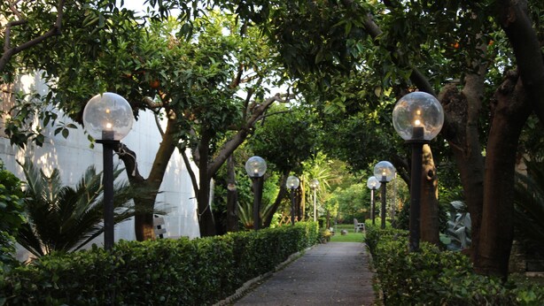 A pathway lined with spherical street lamps and lush greenery. - The Citrus Garden (San Marco Evangelista)